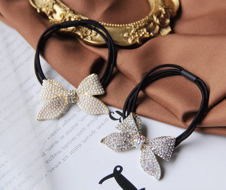Decorative elastic hair bands for women featuring rhinestones, bows, pearls and alloy charms, styled for ponytails and daily fashion use. 