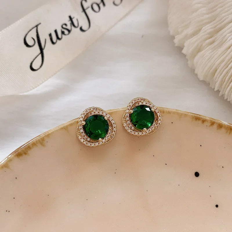 Emerald green halo stud earrings on beige tray