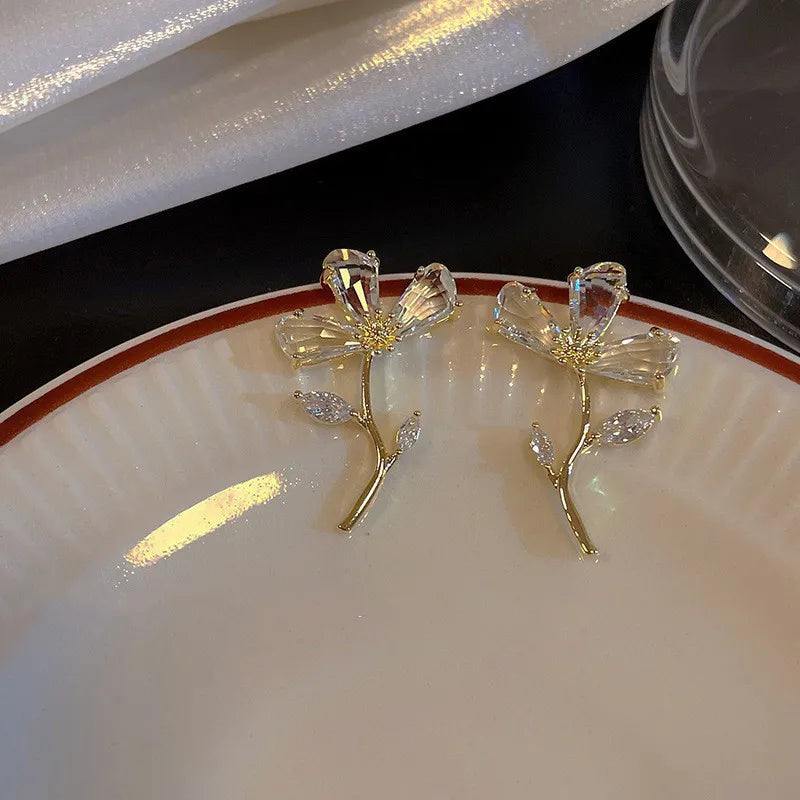 Gold crystal branch stud earrings with CZ stones displayed on plate