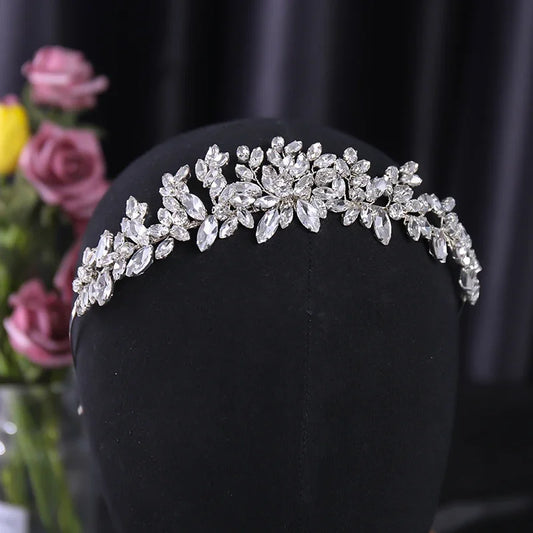 Handmade crystal rhinestone tiara with plant-inspired design on black display stand.