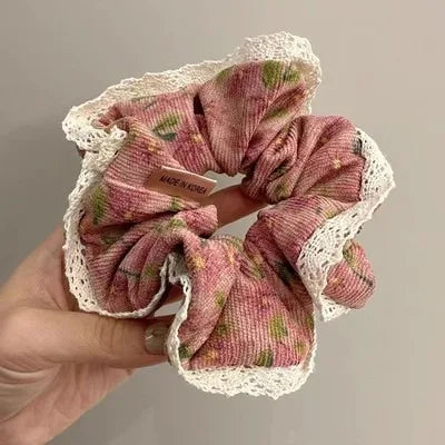 Hand holding soft corduroy floral scrunchie with ribbed texture.