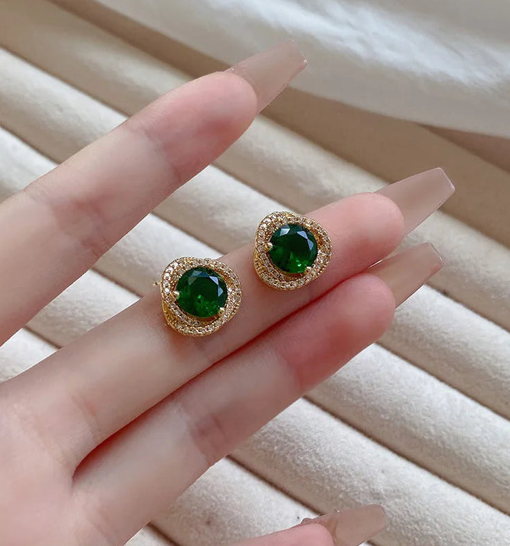 Emerald green vintage stud earrings held by hand