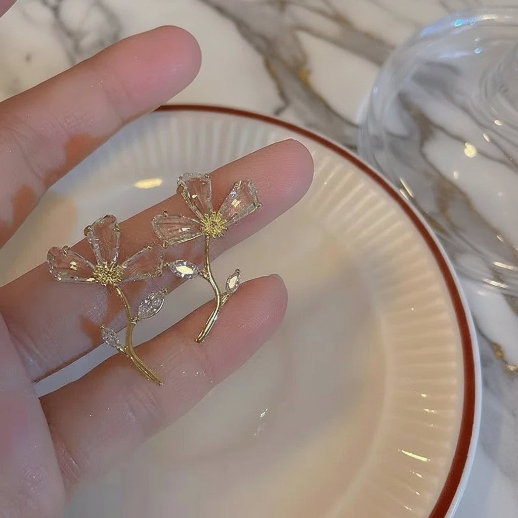 Hand holding gold branch earrings with cubic zirconia details