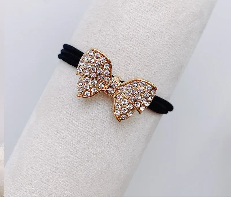 Decorative elastic hair bands for women featuring rhinestones, bows, pearls and alloy charms, styled for ponytails and daily fashion use. 