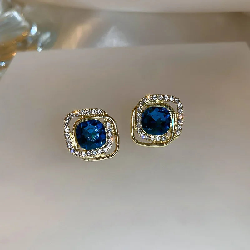 Sapphire blue halo earrings displayed in light