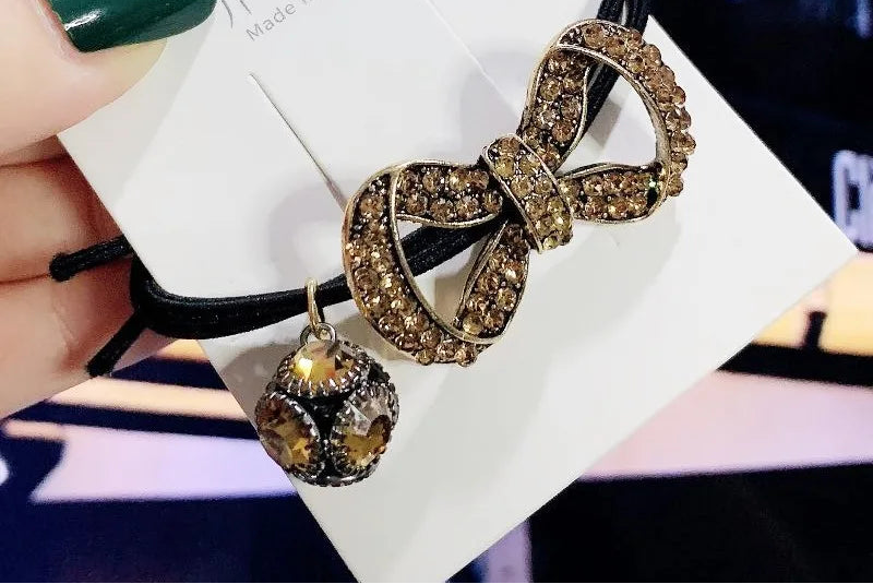 Decorative elastic hair bands for women featuring rhinestones, bows, pearls and alloy charms, styled for ponytails and daily fashion use. 