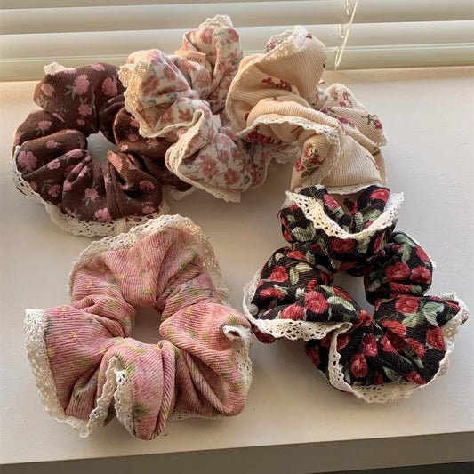 Assorted corduroy floral scrunchies in warm winter colors with lace borders.