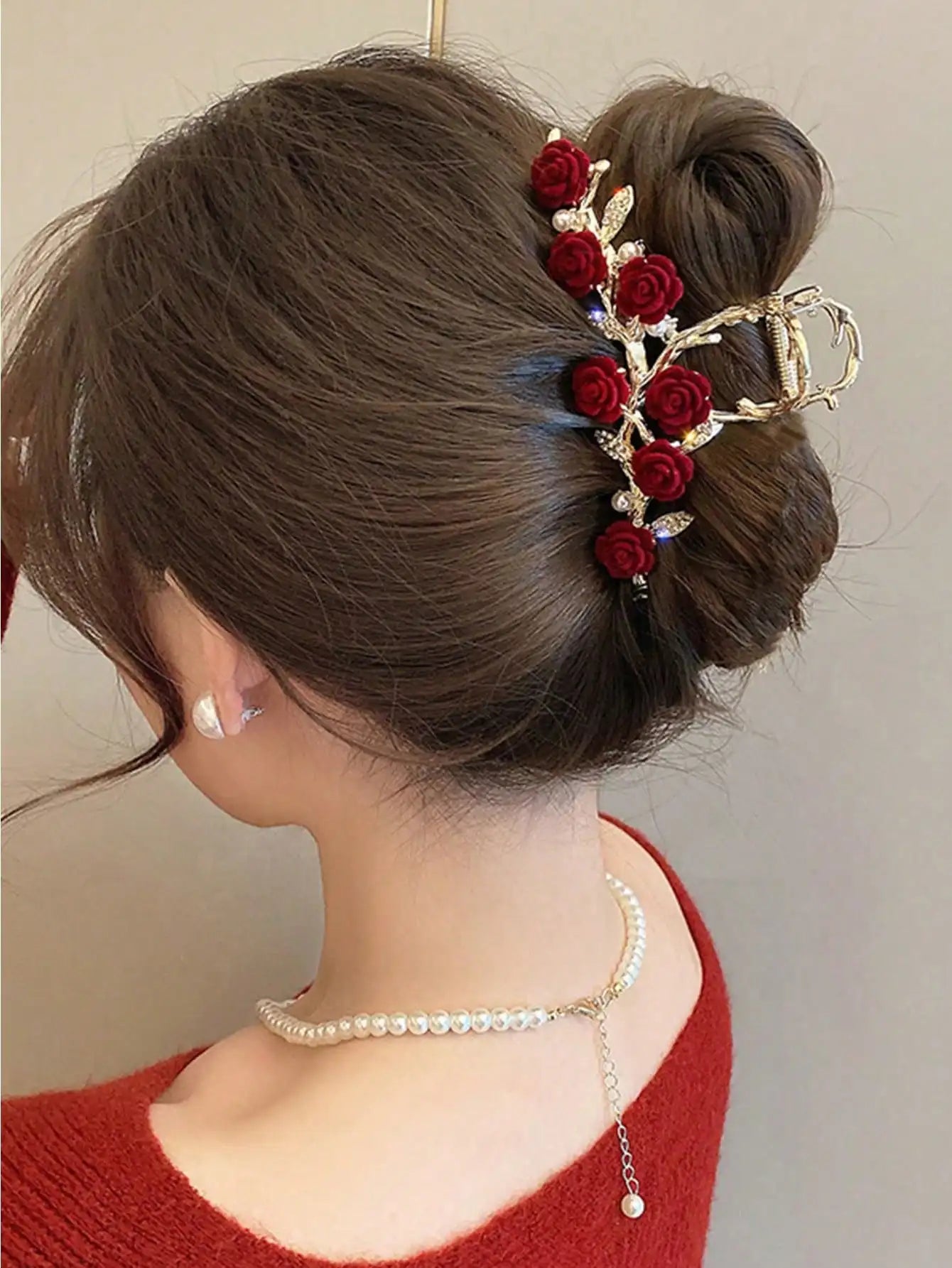 Woman wearing elegant rose hair claw with gold alloy frame and hanging pearl accents.