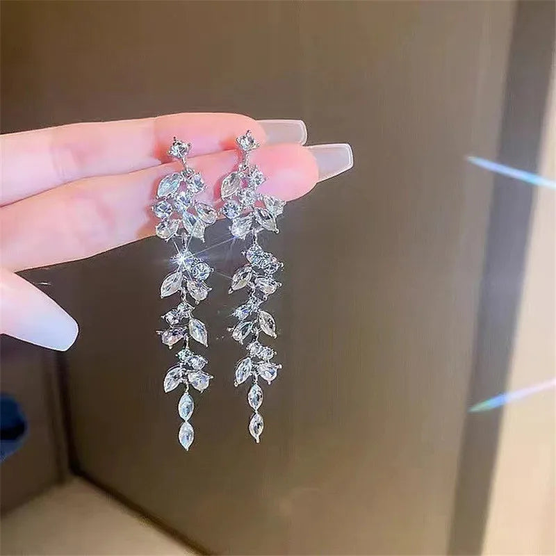 Long chandelier-style crystal earrings held in hand